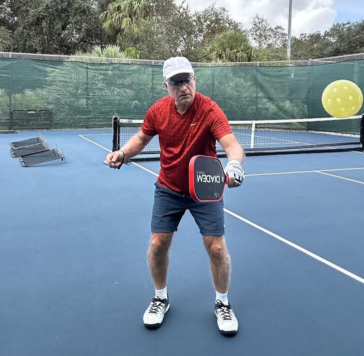 pickleball player using a wall for drilling practice, hitting a pickleball with paddle extended and knees bend