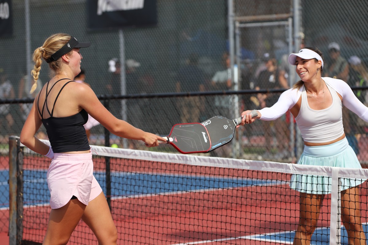 Two pickleball players smiling and tapping paddles during a match at the US Open Pickleball Championships